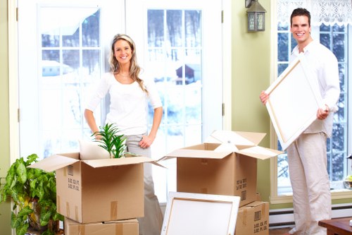 Professional movers carrying belongings through a stairwell in Homerton
